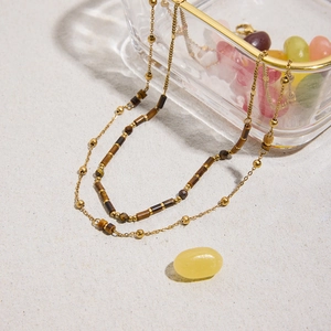 Bohemian gold stainless steel necklace with tiger eye beads on textured background