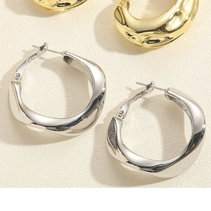 Detailed view of irregular twisted C-shape metal hoop earrings in gold and silver