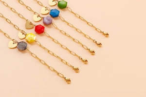 Detailed macro view of colorful geometric beads and heart charms on golden link bracelets