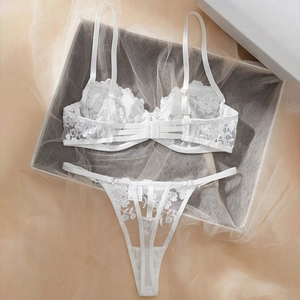 Detail of white lace lingerie set with floral embroidery on a soft tulle background