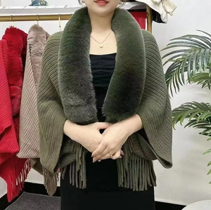 Detail of dark green knit shawl featuring a plush faux fur collar and long fringe trim