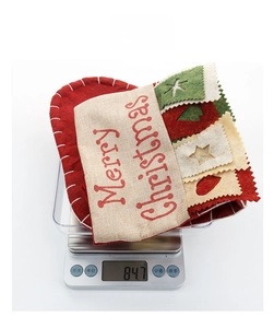 Detailed view of Merry Christmas stocking on digital scale showing a weight of 84.7g