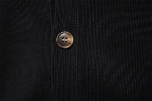 Close-up of fine knit black fabric with a premium brown marbled button detail