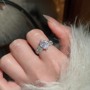 Close-up of sparkling oval zircon ring with pavé diamond band on hand with feather