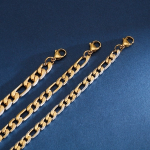 Close-up of gold and silver Figaro link chains with lobster clasps in titanium steel
