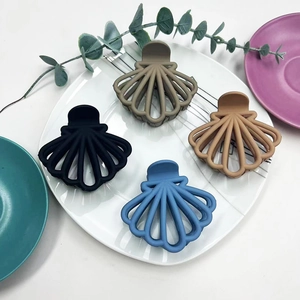 Close-up of four matte shell-shaped hair claws in black, blue, khaki and beige colors