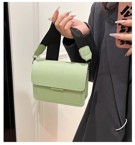 Close-up of mint green faux leather square bag with a black wide shoulder strap
