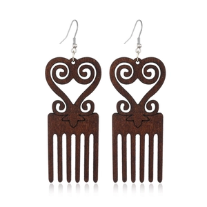 Macro detail of dark brown wooden comb earrings with heart shape and silver hooks