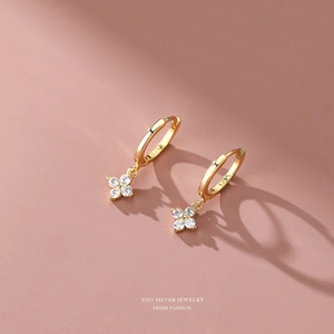 Macro shot of S925 silver gold clover earrings featuring sparkling white zircon stones