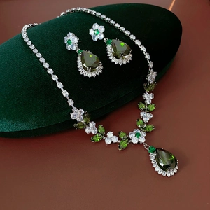 Detail of luxury green zircon flower necklace and earrings on green velvet pad