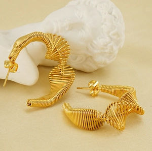 Detail of gold spiral spring hoop earrings with intricate wire-wrapped texture on stone