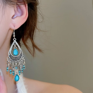 Detail of bohemian silver drop earrings featuring turquoise stones and beaded tassels