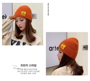Bright orange ribbed knit beanie for winter featuring a square woven patch with text