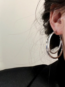Close-up of a model wearing double-layer silver hoop earrings in a minimalist style