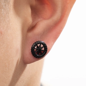Black tire-shaped gear stud earring in stainless steel shown on ear lobe