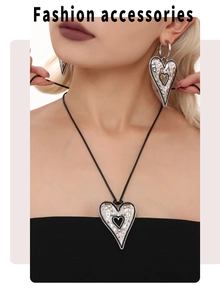 Close-up of hammered heart jewelry set with black enamel detail and black cord necklace