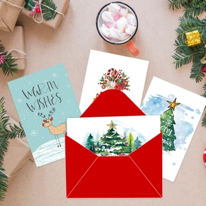 Set de cartes de Noël avec enveloppe rouge, motifs renne et sapin sur table de fête