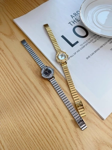 Detailed shot of vintage gold and silver stretch watches with flower bezel on wood surface