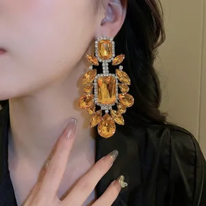 Luxurious water drop geometric earrings with amber stones and white crystals worn by a model