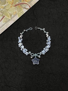 Close-up of blue woven bracelet with small flowers, star pendant and silver bow detail