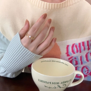 Close-up of a double-layer gold pearl ring worn on finger in a cozy lifestyle setting