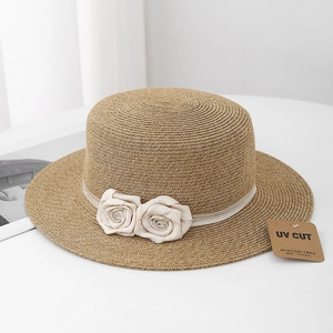 Detail of flat top straw hat featuring a chic ribbon, fabric roses, and UV CUT tag