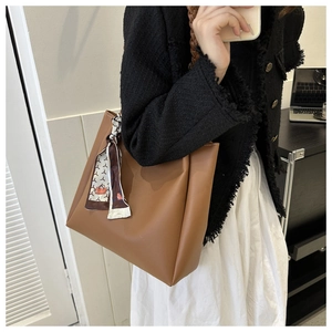Close-up of brown PU leather tote with woven rope handle and decorative printed silk scarf