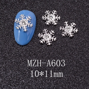 Macro detail of silver snowflake nail art charms with crystal rhinestones on blue nails