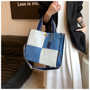 Détail du sac cabas en denim avec finitions dorées et étiquettes en cuir bleu