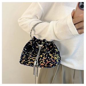 Detail of sequin bucket bag featuring silver ring handle and metallic tassel accents