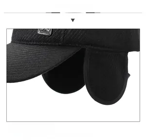 Detail view of winter baseball cap with ear flaps and mountain logo metal badge