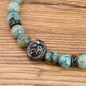 Close-up of vintage 8mm turquoise stone beads and intricate black lion head charm bracelet