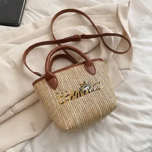 Detail of tiger embroidery on brown straw woven tote bag with faux leather handles
