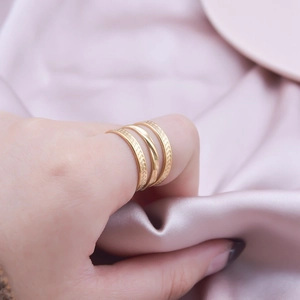 Three minimalist gold adjustable stainless steel rings stacked on a model's finger