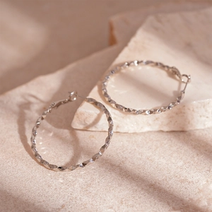 Polished silver geometric hoop earrings with diamond-cut texture on natural stone base