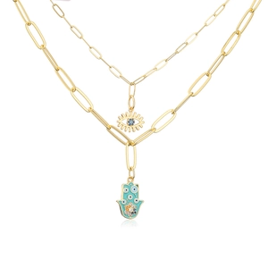 Detail view of 18K gold layered necklace with Hamsa hand and blue evil eye pendants