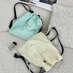 Detailed close-up of lightweight nylon drawstring backpacks in mint green and yellow