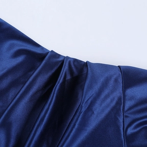Detailed macro view of the blue satin fabric texture and pleated tailoring on this dress