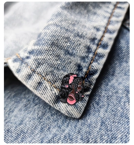 Close-up of a cartoon black girl enamel brooch with pink bow on blue denim jacket lapel