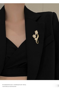 Elegant gold tulip brooch with shimmering crystals and a white pearl on a black suit jacket