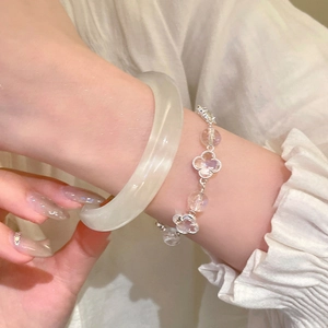 Close-up of white crystal beaded clover bracelet paired with translucent jade bangle