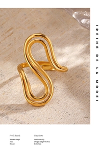 Detailed close-up of a wavy double-layered gold stainless steel ring on a stone base