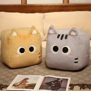 Detail of square ginger and grey cat plush pillows with embroidery on a cozy bed