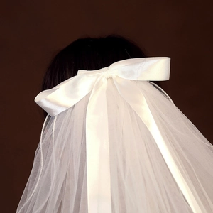 Detail of white bridal veil featuring a double-layered satin bow on soft tulle mesh