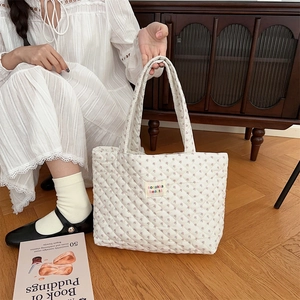 Detailed close-up of a white quilted floral tote bag featuring a brand woven label
