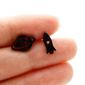 Detail of asymmetric black space earrings with hollow rocket and saturn planet design