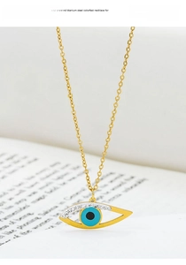 Detail of gold titanium steel evil eye pendant with blue enamel and sparkling rhinestones