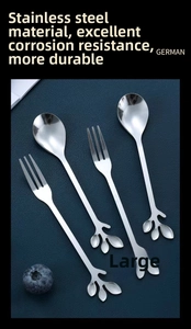 Macro shot of stainless steel leaf handle dessert spoons and forks on dark blue surface