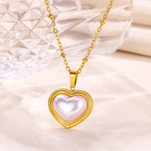 Detail of a golden heart necklace with white pearl inlay on smooth cream silk fabric