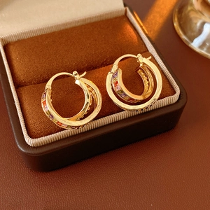 Macro shot of gold earrings with rainbow gemstones in a luxury brown leather gift box